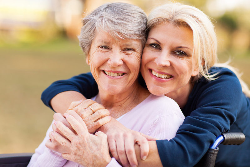 middle aged woman embracing disabled senior mother