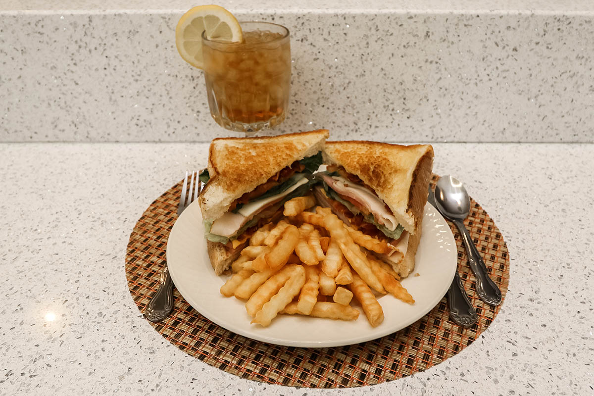 Gourmet sandwich and fries with an iced tea